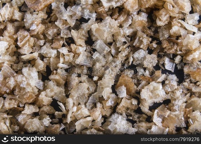 Pile of welsh oak smoked sea salt flakes on dark slate background. The salt is from Anglesey, Wales, United Kingdom, granted EU protected status in 2014. Close up.