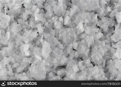 Pile of welsh sea salt flakes on dark slate background. The salt is from Anglesey, Wales, United Kingdom, granted EU protected status in 2014. Close up.