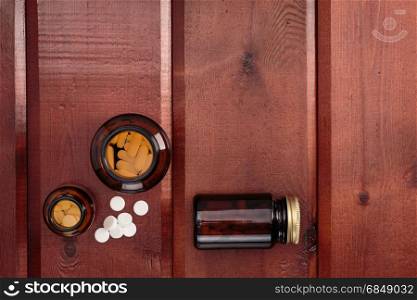 Pile of white pills and glass bottles for medicines.Top view. Heap of white pills and glass bottles for medicines on a wooden background