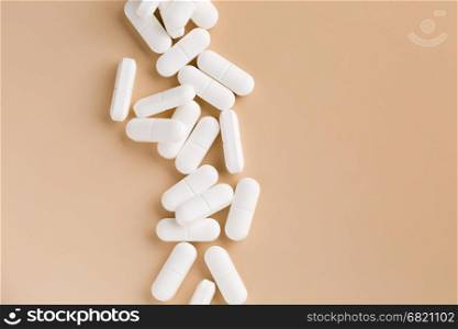 Pile of white pills. Pile of white pills on beige background