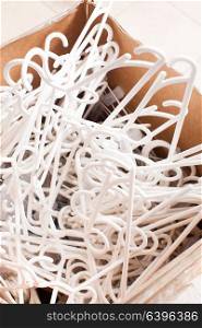 Pile of white plastic clothes hangers in a box close-up. Plastic clothes hangers
