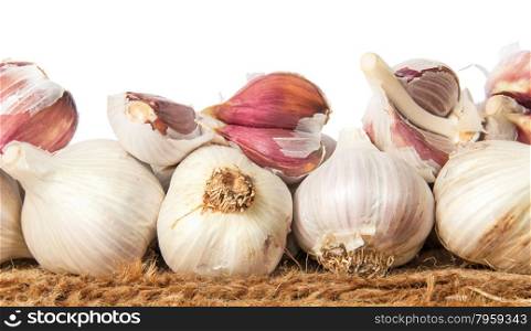 Pile of whole and cloves of garlic on sackcloth isolated on white background