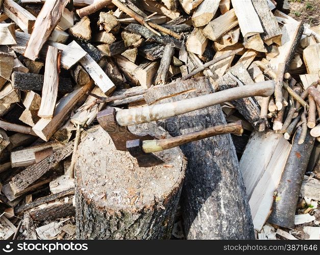 pile of wood, deck for chopping firewood, two axes on village yard