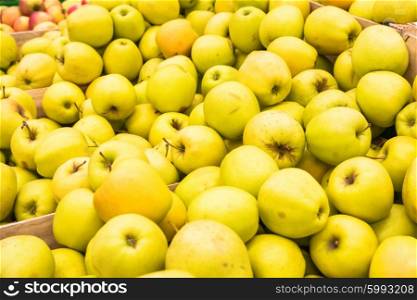 Pile of yellow fresh apples in a wooden crates at farmers market