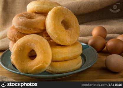 pile off fresh donuts in a plate with some eggs on background