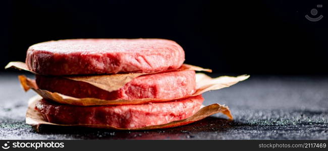 Pile raw burger on the table. On a black background. High quality photo. Pile raw burger on the table.