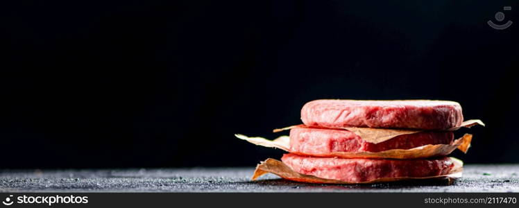 Pile raw burger on the table. On a black background. High quality photo. Pile raw burger on the table.