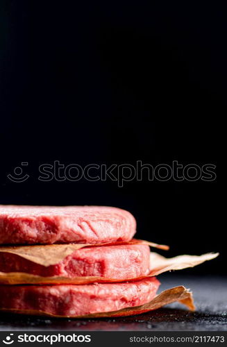 Pile raw burger on the table. On a black background. High quality photo. Pile raw burger on the table.