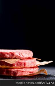 Pile raw burger on the table. On a black background. High quality photo. Pile raw burger on the table.