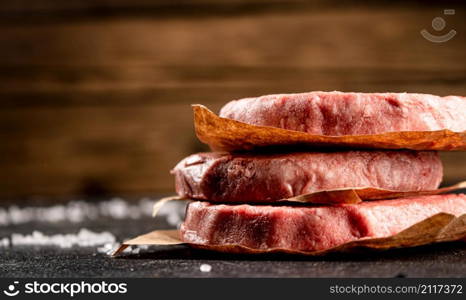 Pile raw burger on the table. On a wooden background. High quality photo. Pile raw burger on the table.