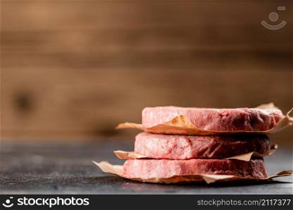 Pile raw burger on the table. On a wooden background. High quality photo. Pile raw burger on the table.