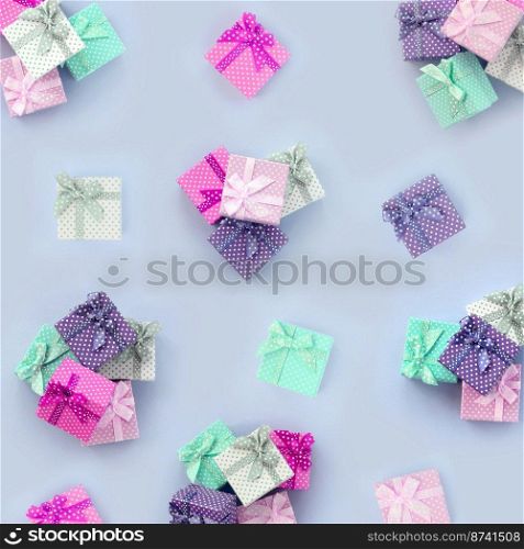 Piles of a small colored gift boxes with ribbons lies on a violet background. Minimalism flat lay top view pattern.. Piles of a small colored gift boxes with ribbons lies on a violet background