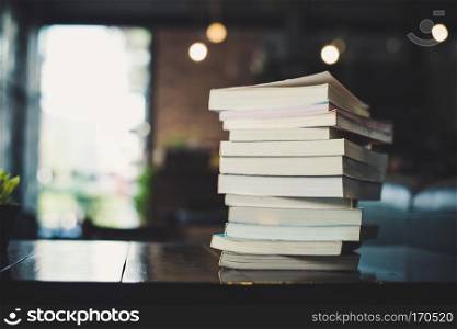 piles of books on table over blurred library background.