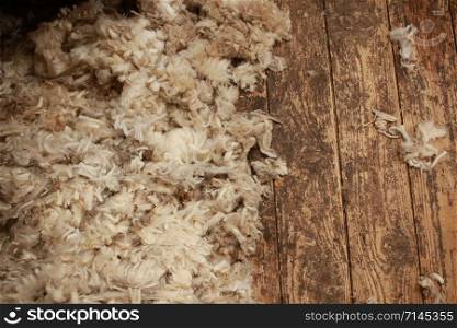 piles of freshly shorn wool scattered on the timber floor of the family farm woolshed shearing shed, rural Victoria, Australia