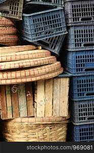 piles of timber and plastic food transport crates piled high by the side of the road at a market in Southeast Asia