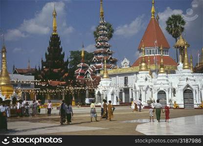 Pilgrims walking in front of a pagoda, Shwedagon Pagoda, Yangon, Myanmar