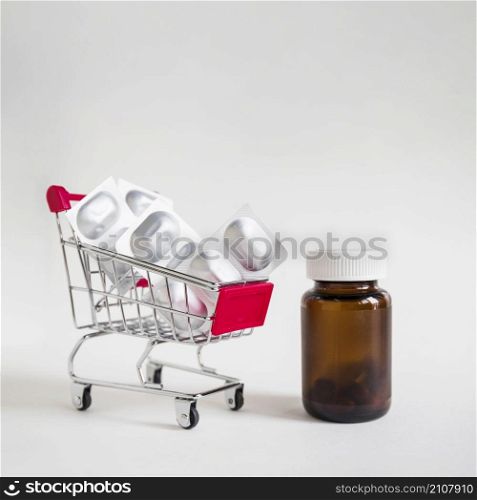 pill blisters shopping cart with glass bottle white background