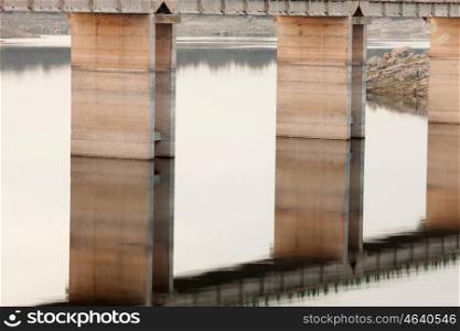 Pillars supporting a bridge over the Tagus river in Extremadura, reflected in the water