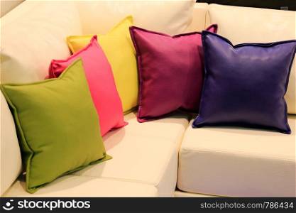 Pillows of different colors on the leather sofa.