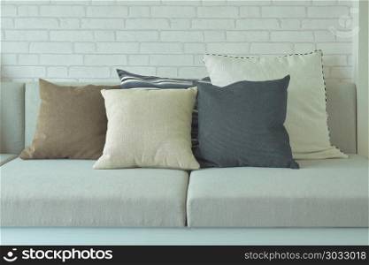Pillows on beige cushion with white brick wall in background