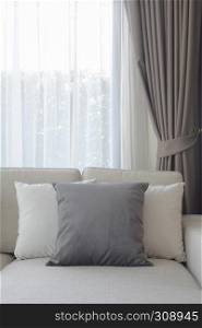Pillows setting on couch with dark gray curtain in background
