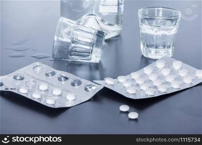 Pills and alcohol on a grey table. Concept for drug abuse.