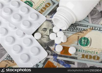 Pills and bottle on new hundred dollar bills, medicine and health care cost concept