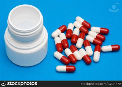 Pills and empty container of pills over blue background