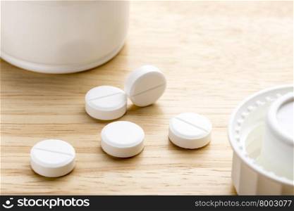 Pills and pill bottle on wooden background. Pills and open pill bottle on wooden background