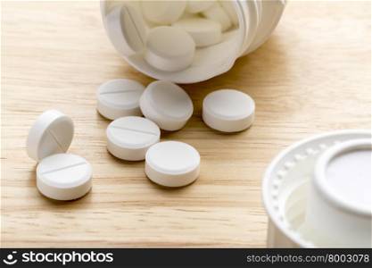 Pills and pill bottle on wooden background. Pills and open pill bottle on wooden background