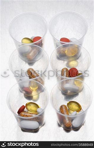 Pills and tablets in six plastic cups