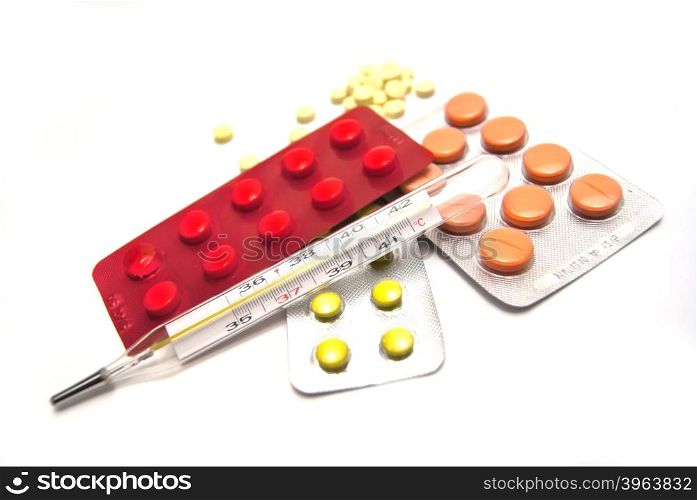 Pills and thermometer on white background