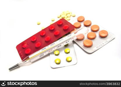 Pills and thermometer on white background