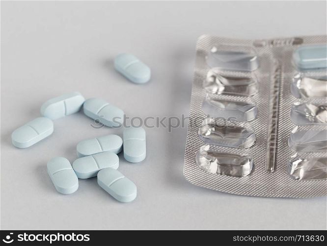 Pills blister pack and blue tablets on colored background. Pills blister pack and blue tablets