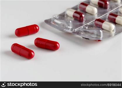 Pills blister pack and three red capsules. Pills blister pack and three red capsules on white background
