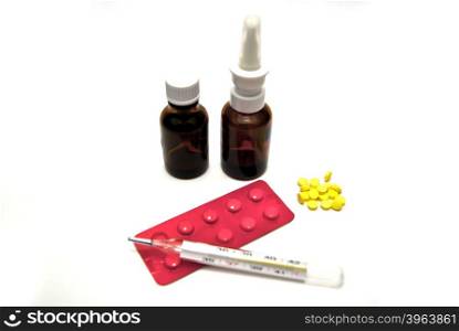 Pills, bottles, and thermometer on white background