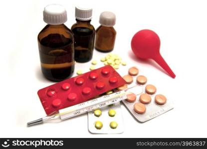 Pills, bottles, enema and thermometer on white background