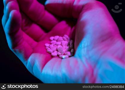Pills heap in hand blue and pink light