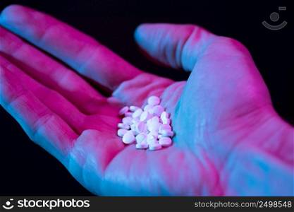 Pills in hand. Drug tablets in palm close-up on dark background