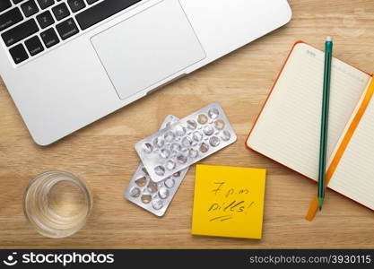 Pills,laptop, notepad with pencil and glass of water