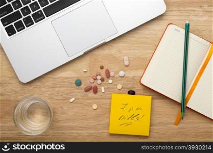 Pills,laptop, notepad with pencil and glass of water