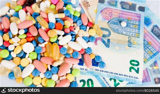 Pills of different colors on money