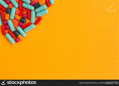 Pills of differents colors on an orange background