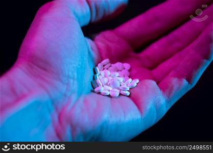 Pills pile in hand. Drug tablets in palm close-up on dark background