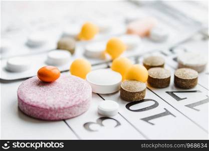 Pills, supplements and medicines for the disease. A pile of different pills on a calendar background. Healthcare. Pills, supplements and medicines for the disease. A pile of different pills on a calendar background.
