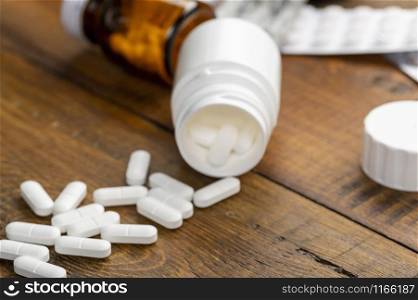 Pills white, blister pack and different medicine bottles. Dark wooden background. Pills white, blister pack and different medicine bottles