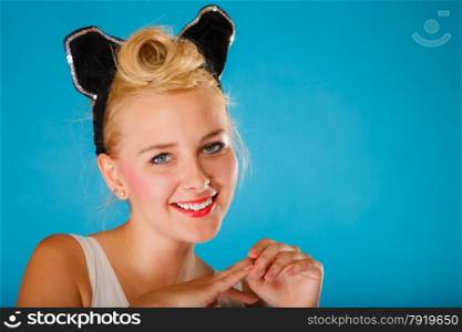 Pin up and retro style. Young smiling woman with black ears on head on blue background. Studio shot.