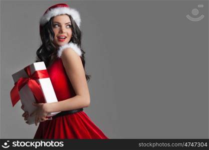 Pin-up Santa girl. Excited surprised woman in red santa claus outfit holding Christmas present