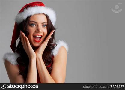 Pin-up Santa girl. Pretty Pin-up style Santa girl in red hat on gray background