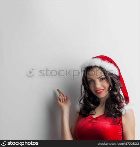 Pin-up Santa girl. Pretty Pin-up style Santa girl in red hat pointing to white background